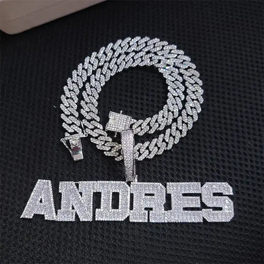 Iced out silver Cuban chain with custom CZ nameplate pendant spelling ANDRES on black background