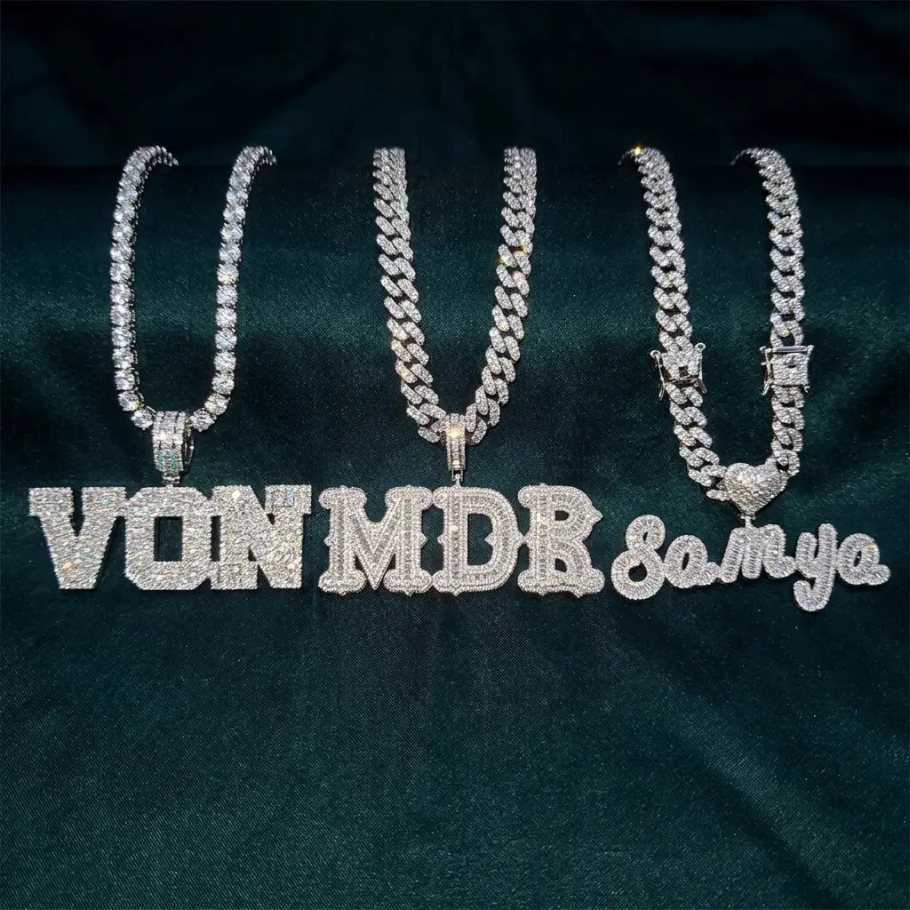Three custom iced out name necklaces side by side — block letters, gothic letters, and cursive script — fully set with CZ stones on Cuban and tennis chains