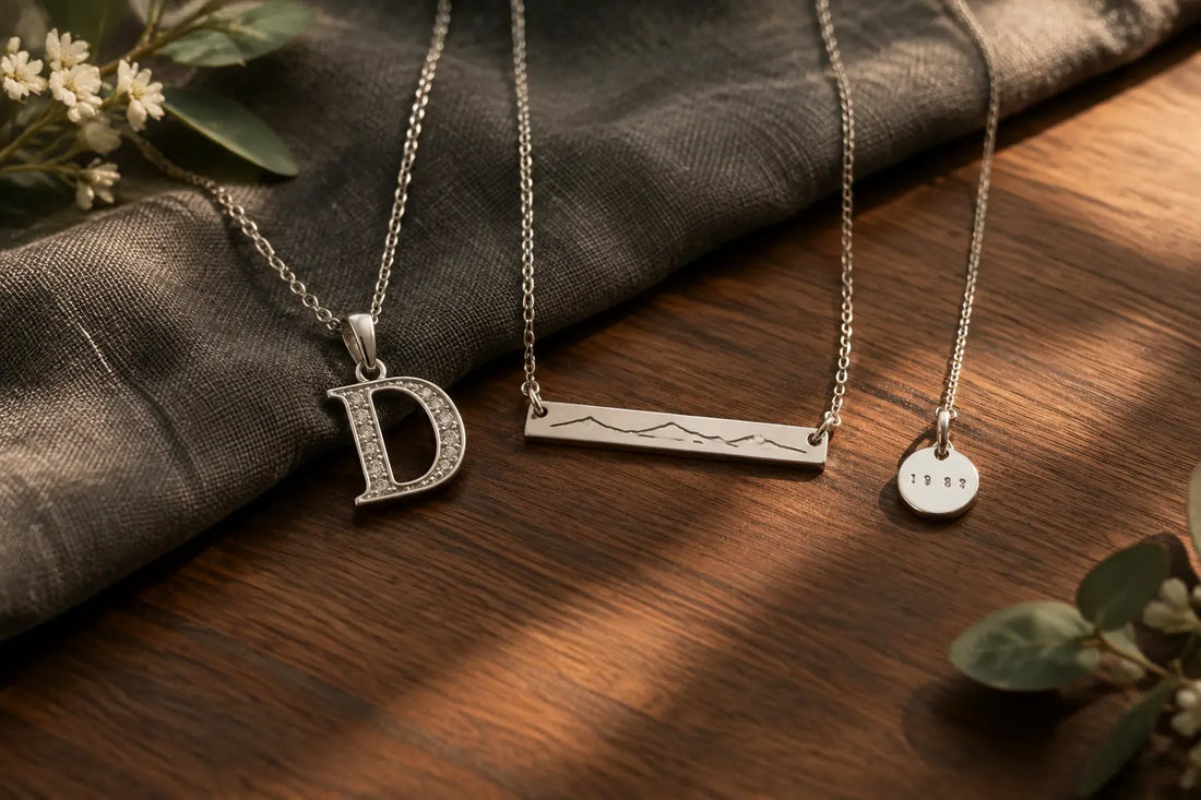 Silver memorial necklaces for dad with initial, surname bar, and year charms on walnut and gray linen