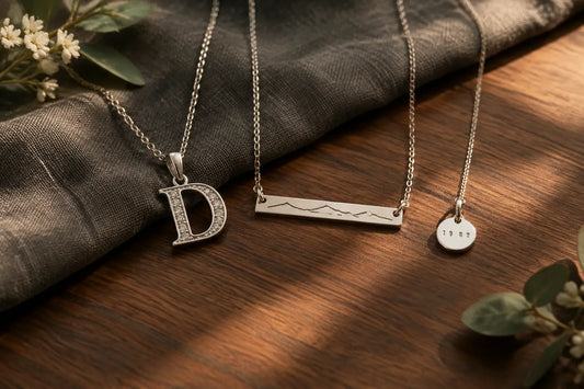 Silver memorial necklaces for dad with initial, surname bar, and year charms on walnut and gray linen