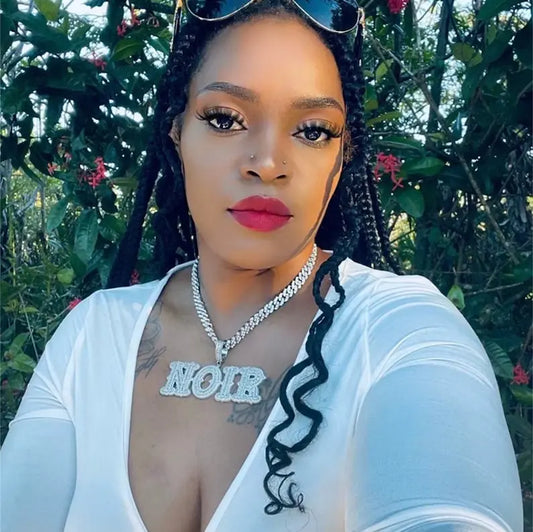 Woman wearing iced out custom block letter name pendant NOIR on Cuban link chain — 5A CZ rapper pendant streetwear style