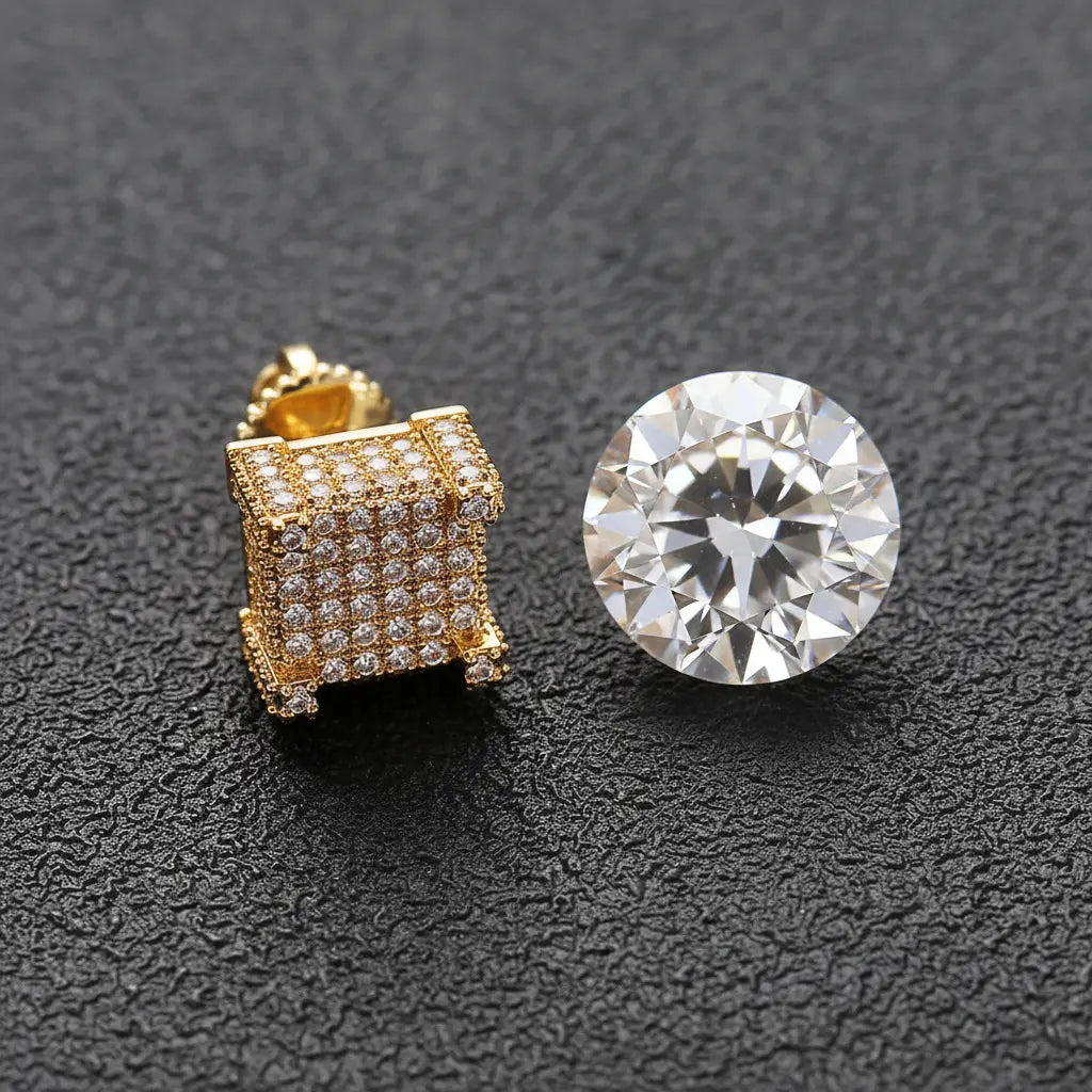 Gold iced-out CZ square stud earrings next to a loose diamond on dark background — CZ vs diamond comparison